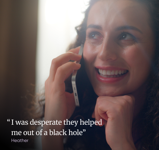A woman smiling while talking to a debt advisor on her phone, with the testimonial: "I was desperate, they helped me out of a black hole", Heather